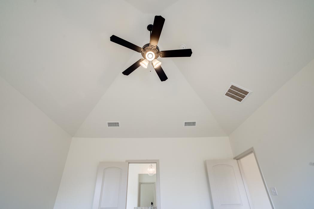 Spacious bedroom with vaulted ceiling and ceiling fan in new home for sale in Lubbock, Texas.