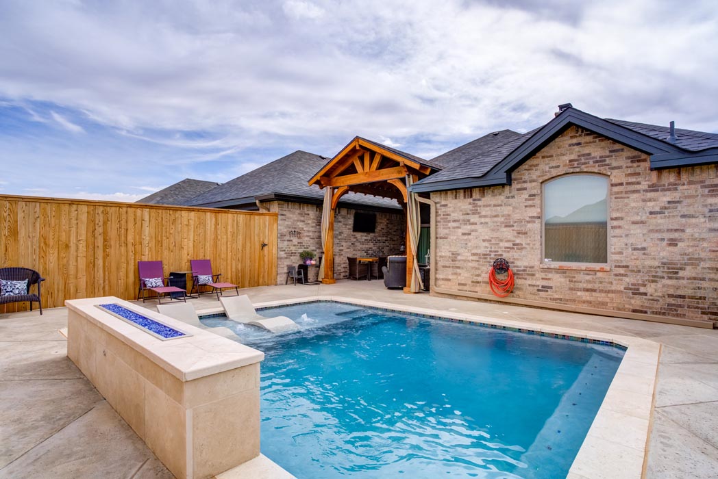 Beautiful swimming pool with fire ledge in new Lubbock home for sale.