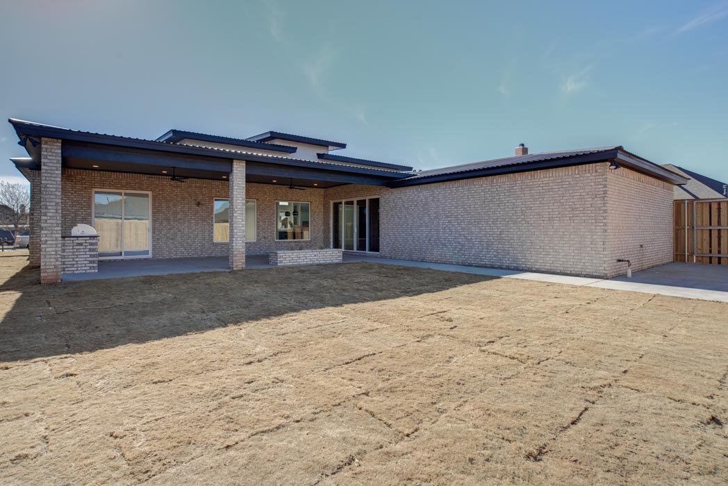 View of spacious backyard and covered patio area of new Lubbock, Texas home.