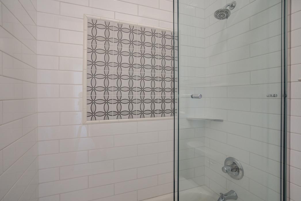 Glass shower with beautiful tile treatment in bath of Lubbock home.