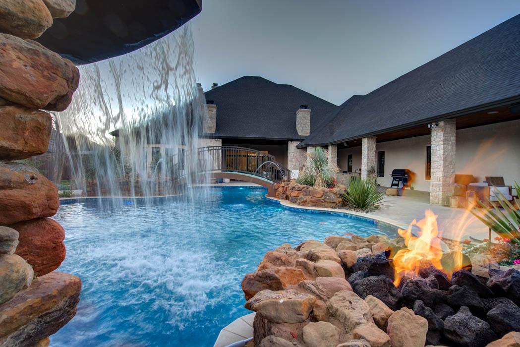 View of water plunging over waterfall in custom swimming pool in custom-built home near Lubbock.
